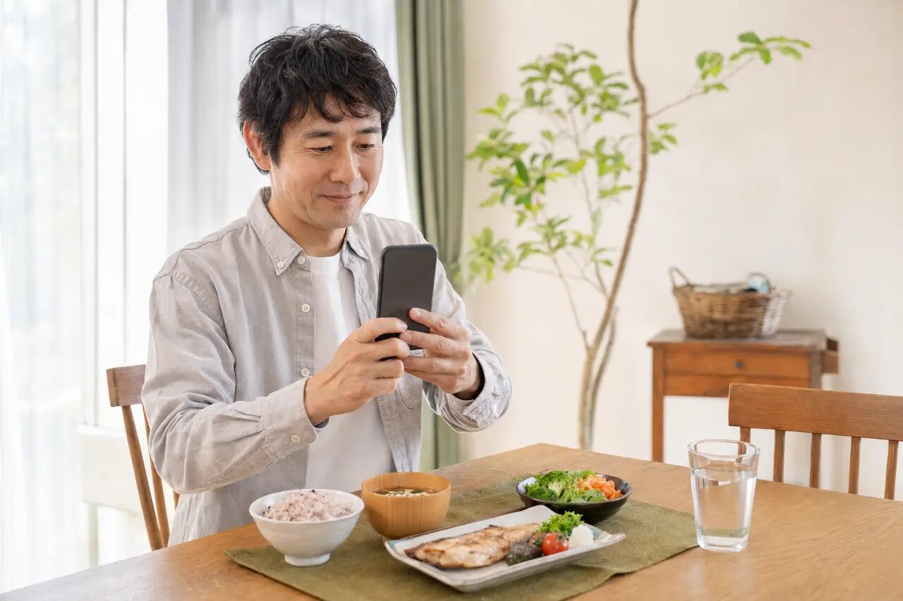 食事をスマートフォンで撮影する男性